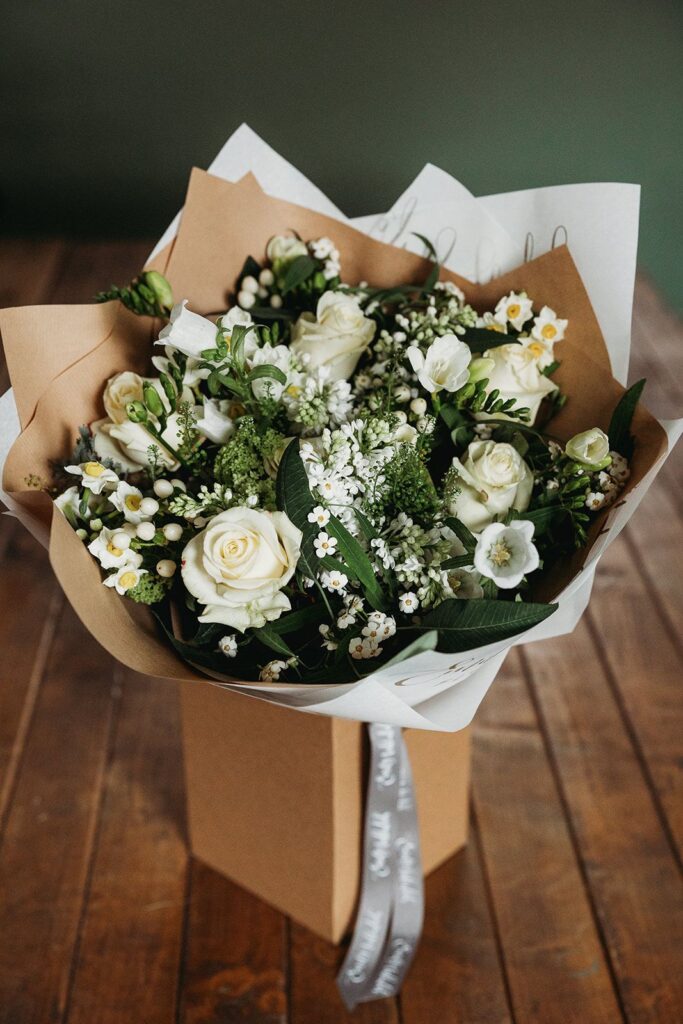 Spring white flower bouquet with roses, narcissi and seasonal foliage in a gift box